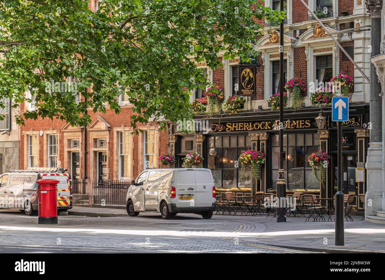 Londres, Reino Unido- 4 de julio de 2022: Sherlock Holmes Pub en Northumberland Street bajo follaje verde y coches estacionados en frente. Foto de stock