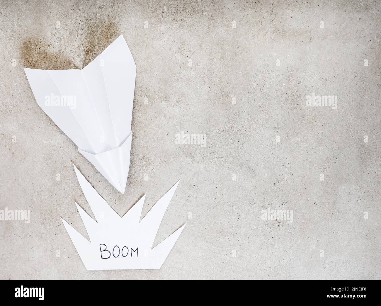 Avión de papel como metáfora, rumbo a un accidente o explosión, en gris con espacio de copia Foto de stock
