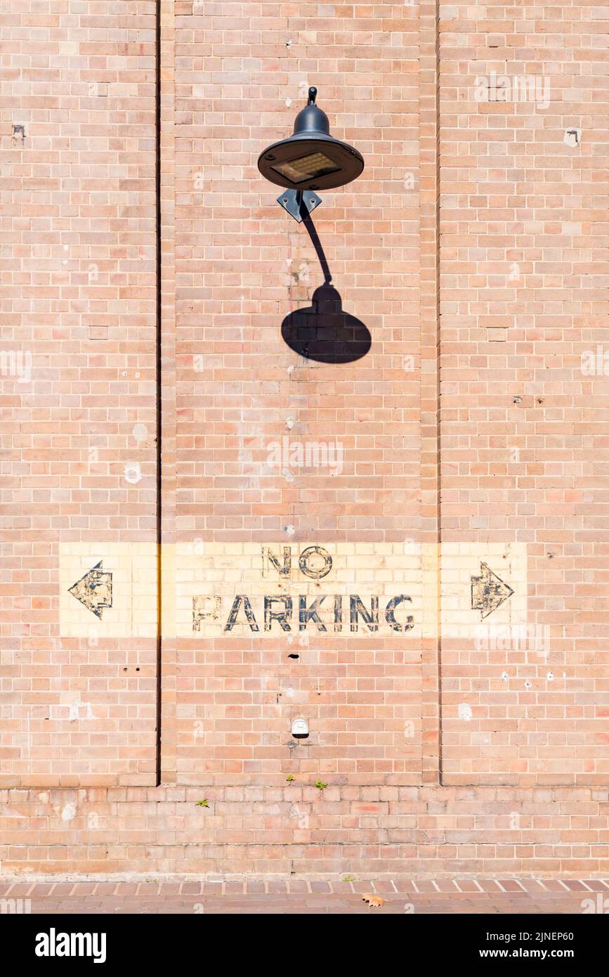 Una pared alta de ladrillo con un foco LED de estilo antiguo y un cartel clásico de No Parking en el National Innovation Centre en South Eveleigh, Sydney Foto de stock