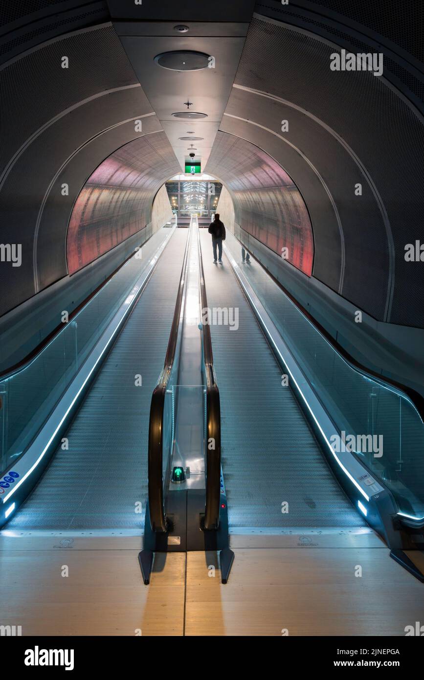 Un hombre con siluetas caminando sobre un viajero o escalera mecánica en un túnel en South Eveleigh en Sydney, Australia Foto de stock