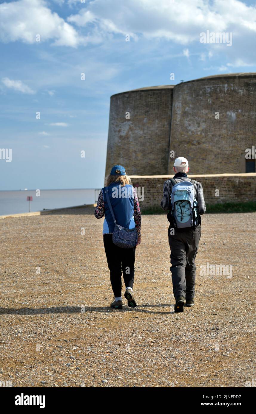 dos excursionistas caminando hacia la torre martello aldeburgh suffolk inglaterra Foto de stock