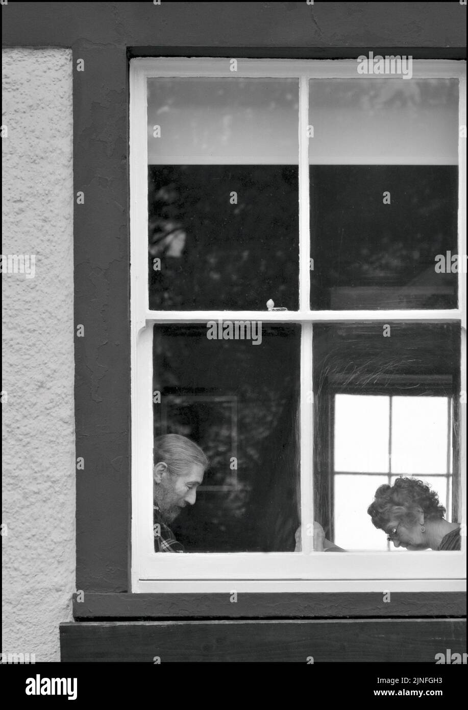 Hombre y mujer sentados leyendo en la ventana de la cabaña Foto de stock