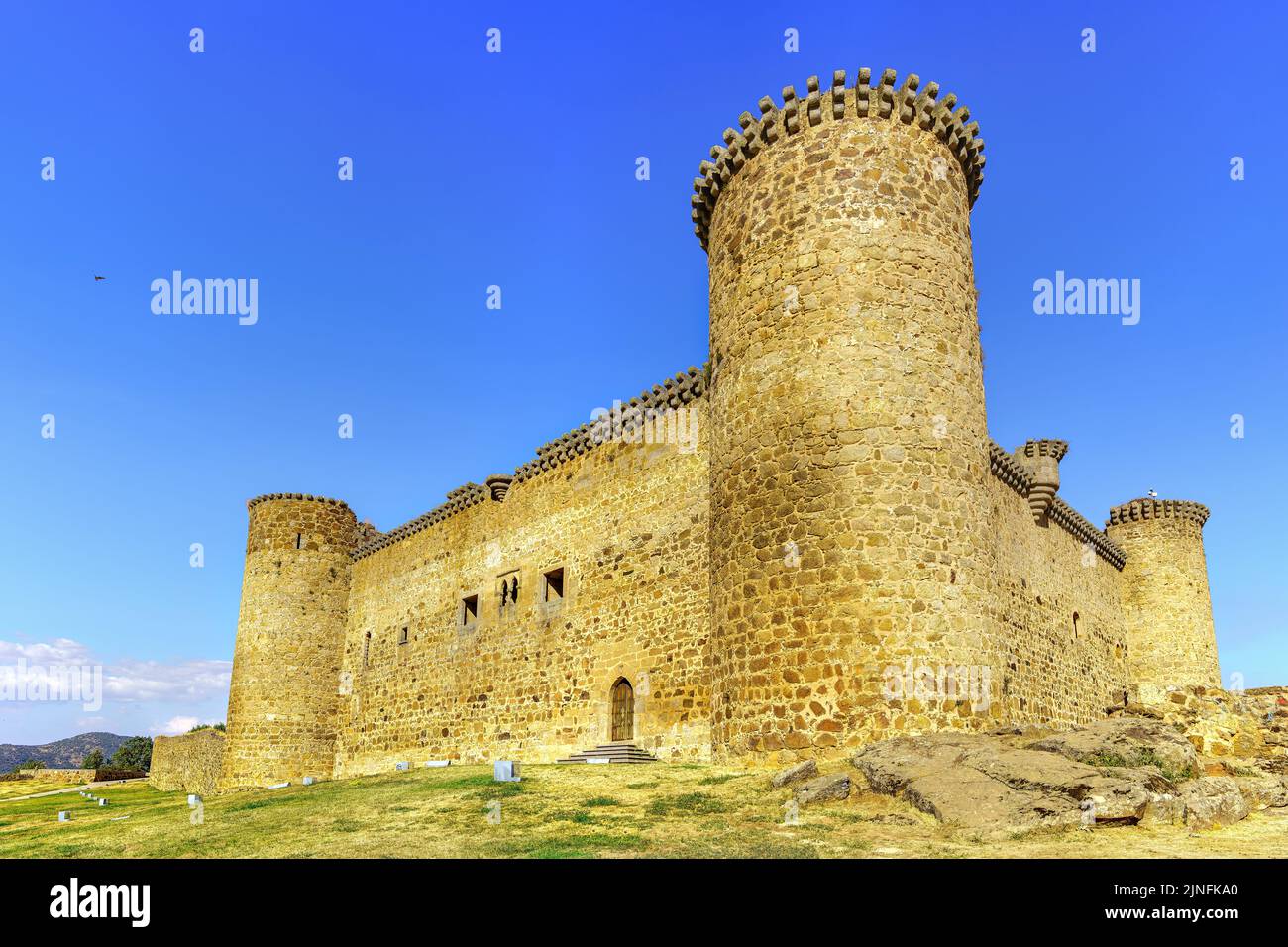 Castillo medieval con sus altas torres de piedra en las esquinas del recinto en un día con cielo azul, Barco Ávila, España. Foto de stock