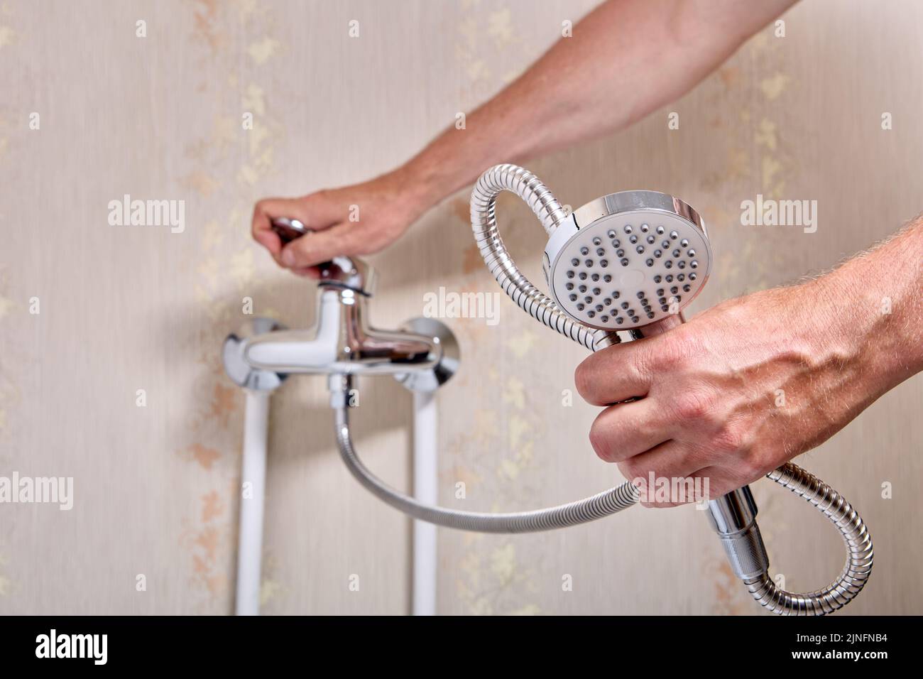Fontanero arreglando el grifo de la ducha con un solo mango que goteaba en el baño. Foto de stock