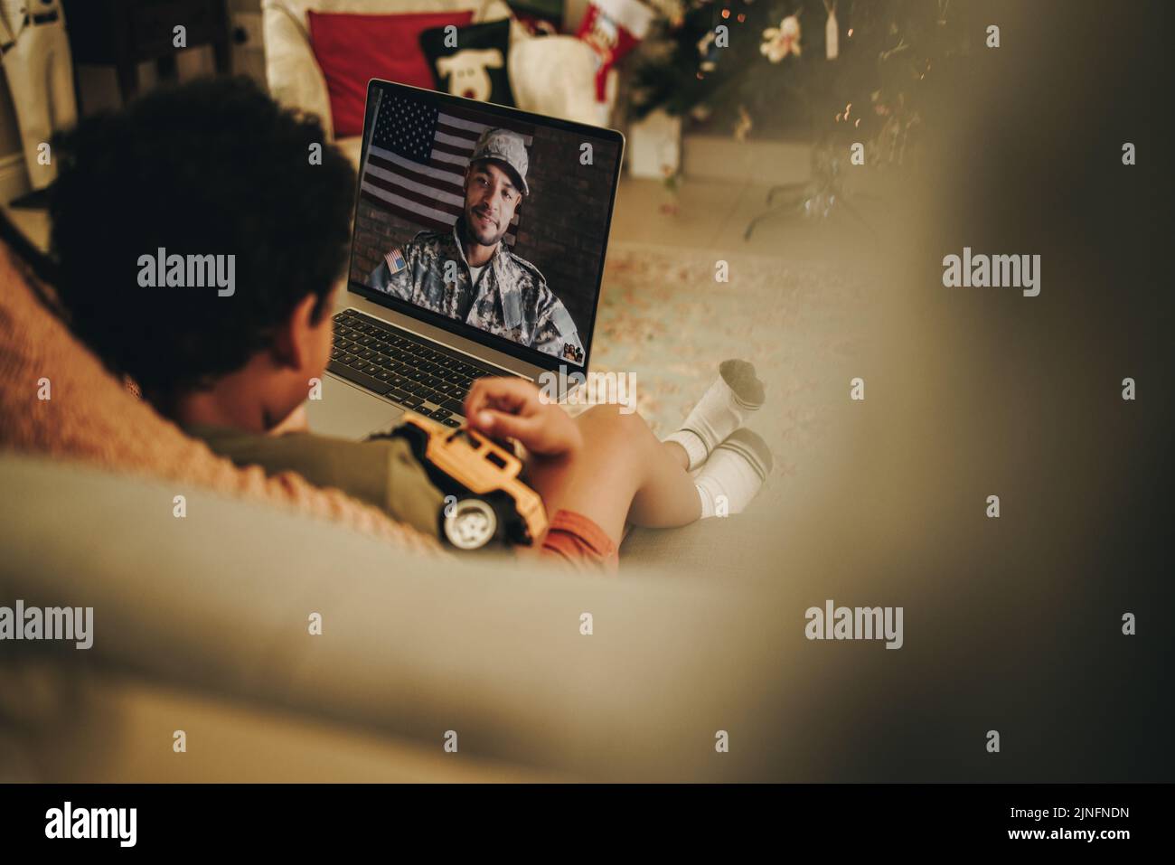 Video de niño llamando a su padre militar en Navidad. Joven en comunicación con su padre en un ordenador portátil. Familia militar teniendo un hueco en línea Foto de stock