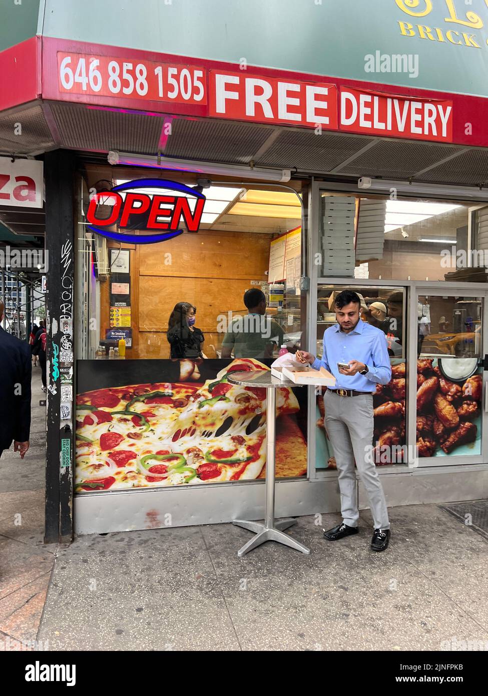 Un trabajador de Midtown come pizza durante su almuerzo en Manhattan, Nueva York. Foto de stock