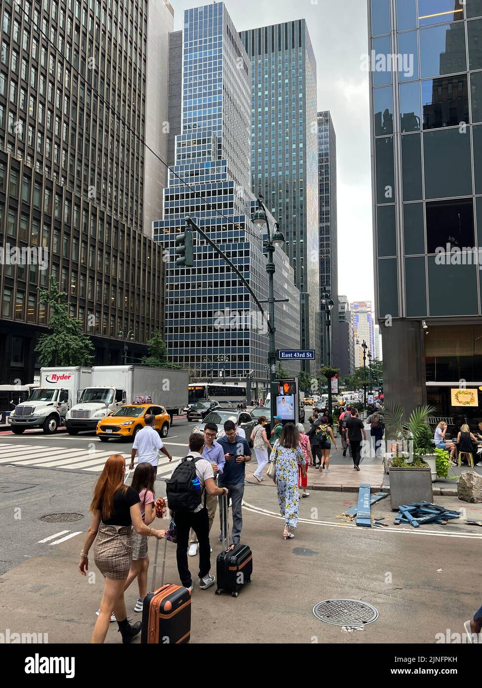 Mirando al centro a lo largo de la 6th Avenida de la calle 43rd pasando el canyoun de edificios de oficinas en el área en el centro de Manhattan. Foto de stock
