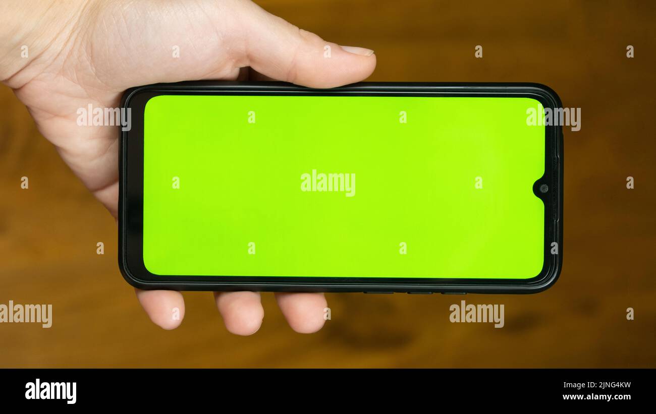 teléfono móvil con tecla de color verde en la pantalla táctil en manos de la mujer. Foto de stock