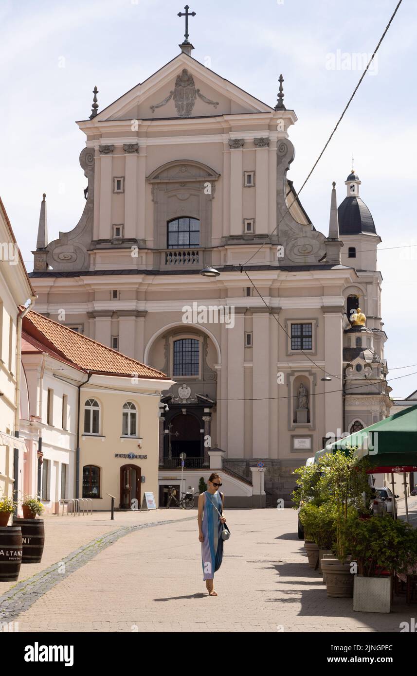 Vilnius Old Town escena callejera con la Iglesia de Santa Teresa y una mujer caminando, en verano, Vilnius, Lituania Europa Foto de stock