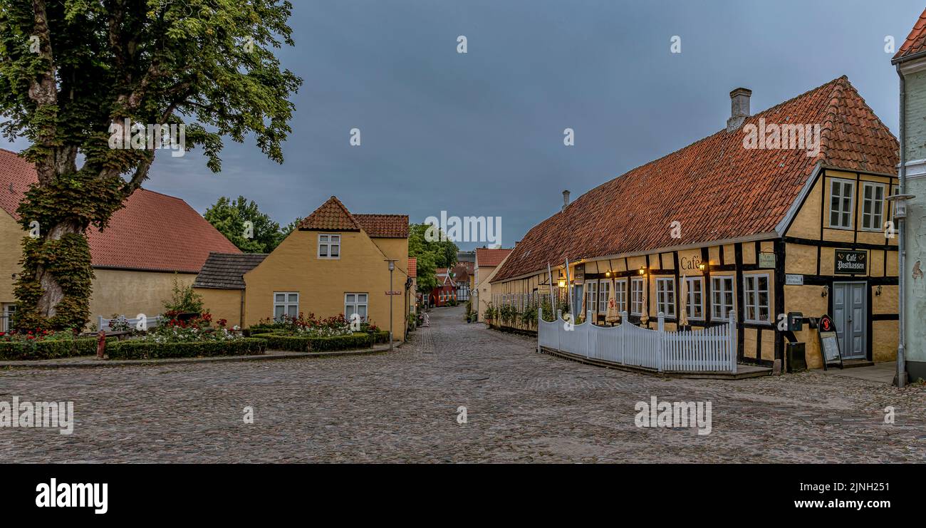 Vista panorámica de una plaza de adoquines y el hotel Postgaarden de madera antigua a la luz del atardecer, Mariager, Dinamarca, 7 de agosto de 2022 Foto de stock
