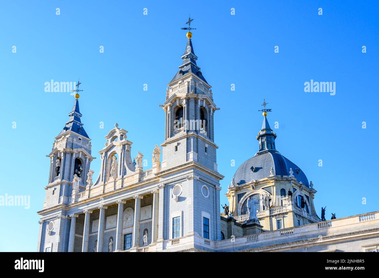 Catedral de la Almudena (Santa María la Real de La Almudena). Los dos campanarios y la cúpula en un cielo azul. Foto de stock