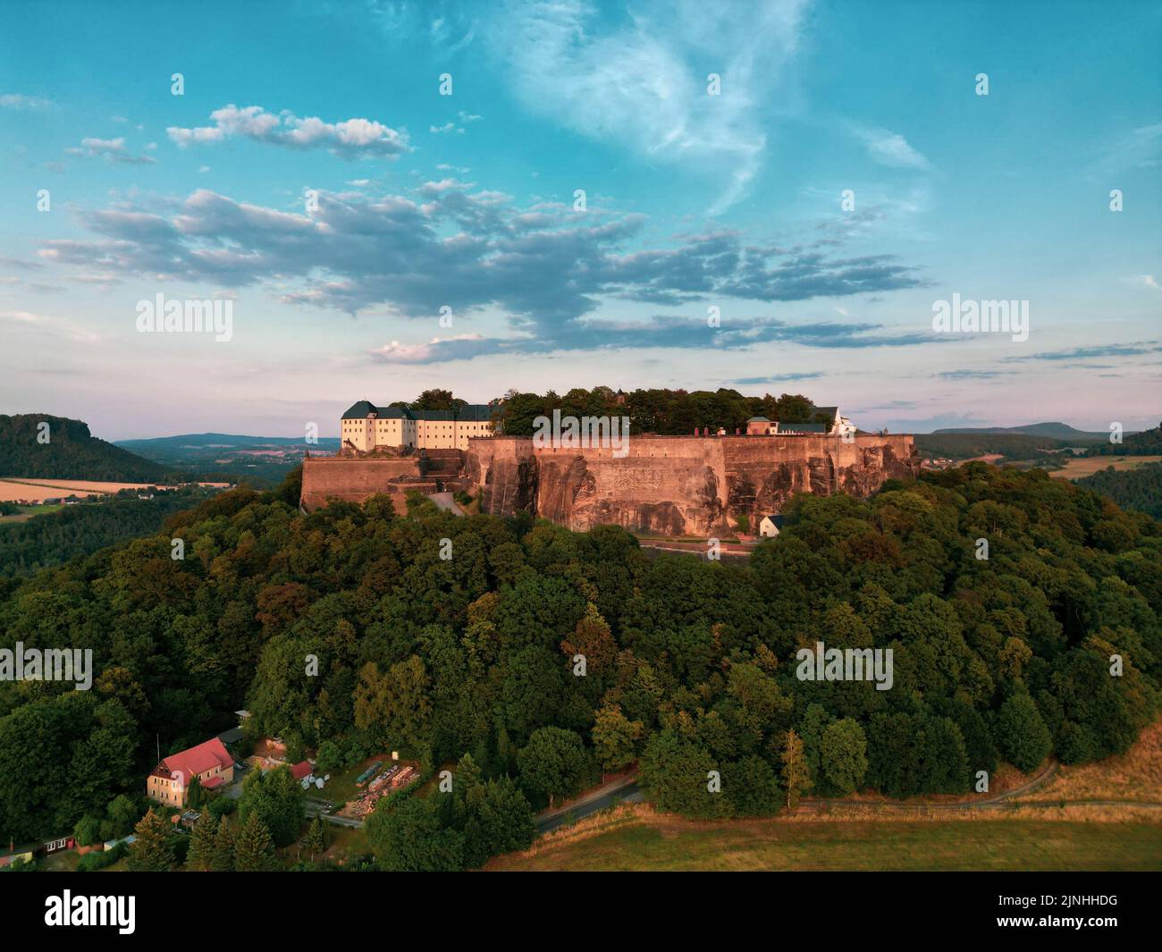 Una vista impresionante de la Fortaleza de Konigstein en Sajonia, Alemania que se alza orgullosa entre densos árboles Foto de stock