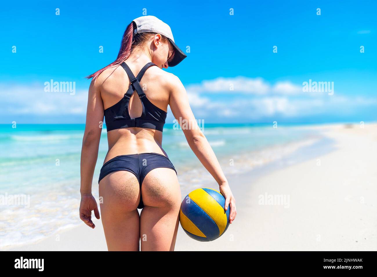 Joven atleta en la playa en verano con una pelota de voleibol contra el fondo del hermoso mar Caribe Foto de stock