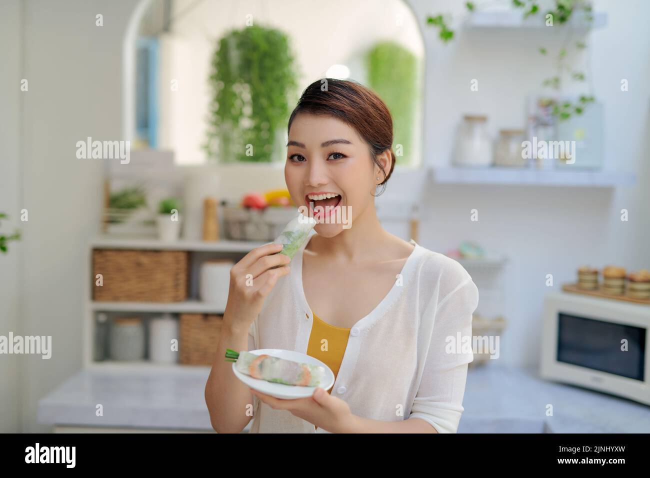 Mujer asiática comiendo sabrosos rollitos de primavera tradicionales Foto de stock