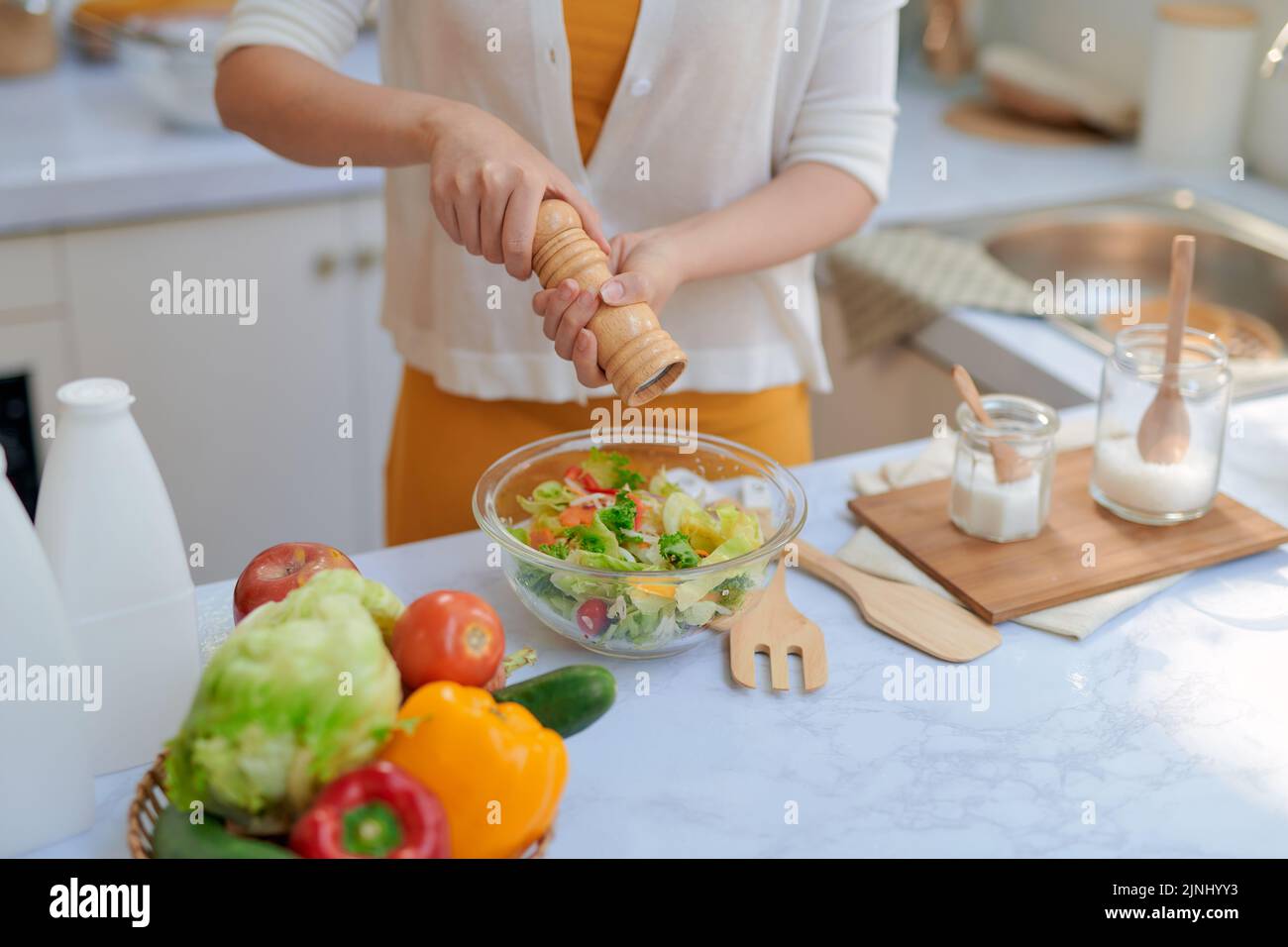 Primer plano de la sección media de un chef poniendo sal y pimienta en la cocina Foto de stock