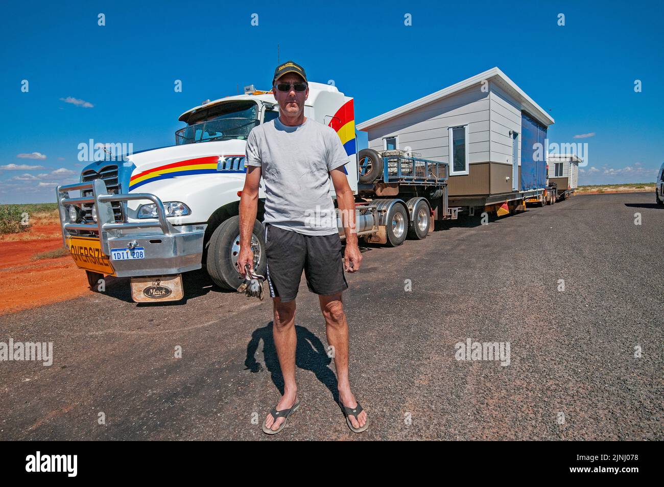 Conductor de camiones en tránsito transportando viviendas prefabricadas en dos secciones en camiones desde Perth, para ser montado en una ciudad minera cerca de Karratha en Australia Occidental Foto de stock
