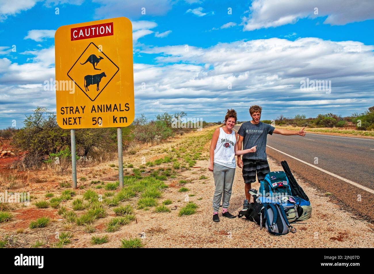 Un par de jóvenes mochileros británicos esperando un ascensor en la autopista cerca de Monkey Mia en Australia Occidental Foto de stock