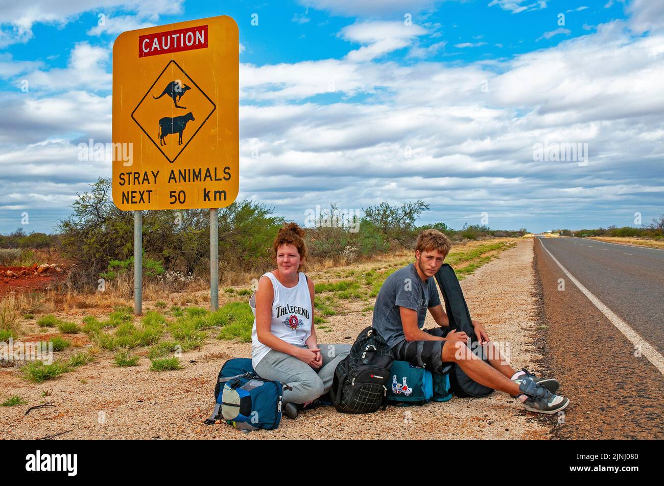 Un par de jóvenes mochileros británicos esperando un ascensor en la autopista cerca de Monkey Mia en Australia Occidental Foto de stock