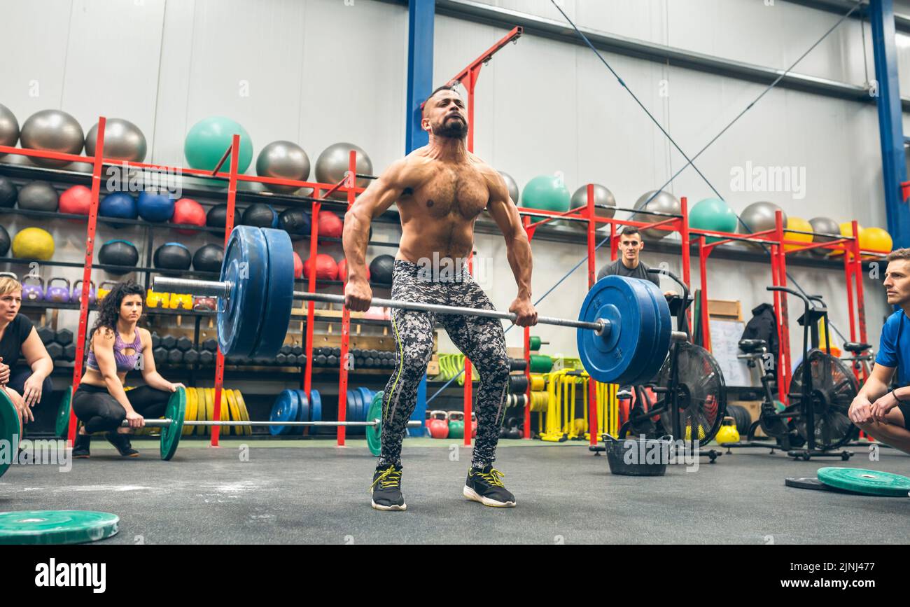 Hombre fuerte practicando el levantamiento de pesas en el gimnasio Foto de stock
