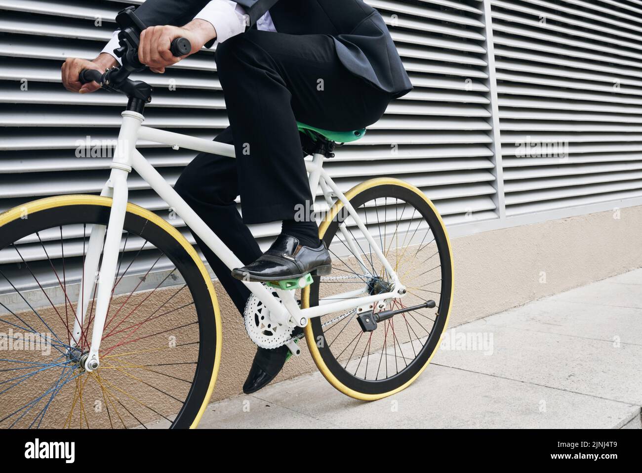 Hombre de negocios con estilo en traje de ciclismo en bicicleta en carretera  pavimentada al aire libre