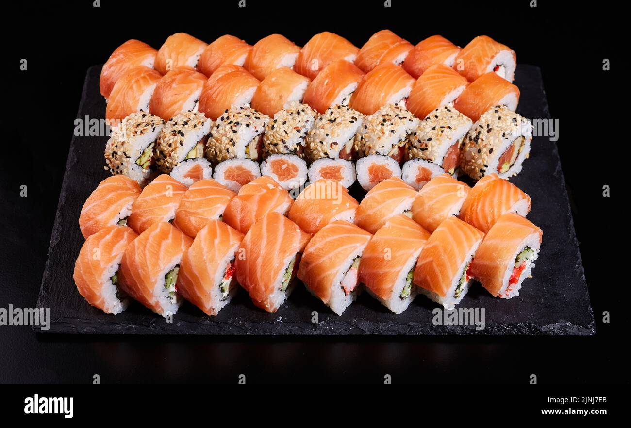 Sushi Set que consiste en un gran número de papeles de Filadelfia con salmón crudo y otros sushi en el medio. Juego de sushi japonés. Diferentes tipos de Foto de stock