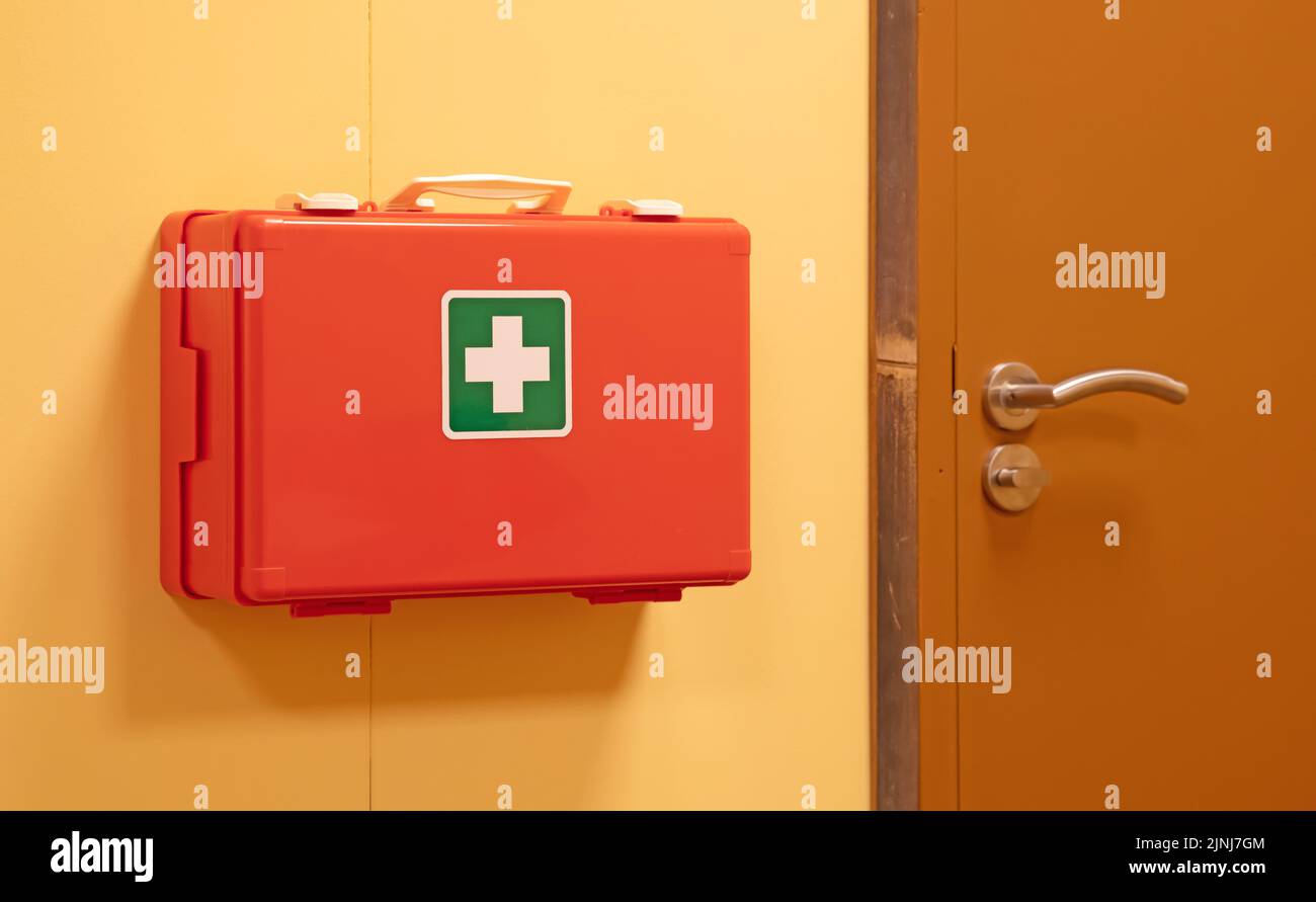 Caja naranja de primeros auxilios colgando en la pared para medidas de seguridad Foto de stock