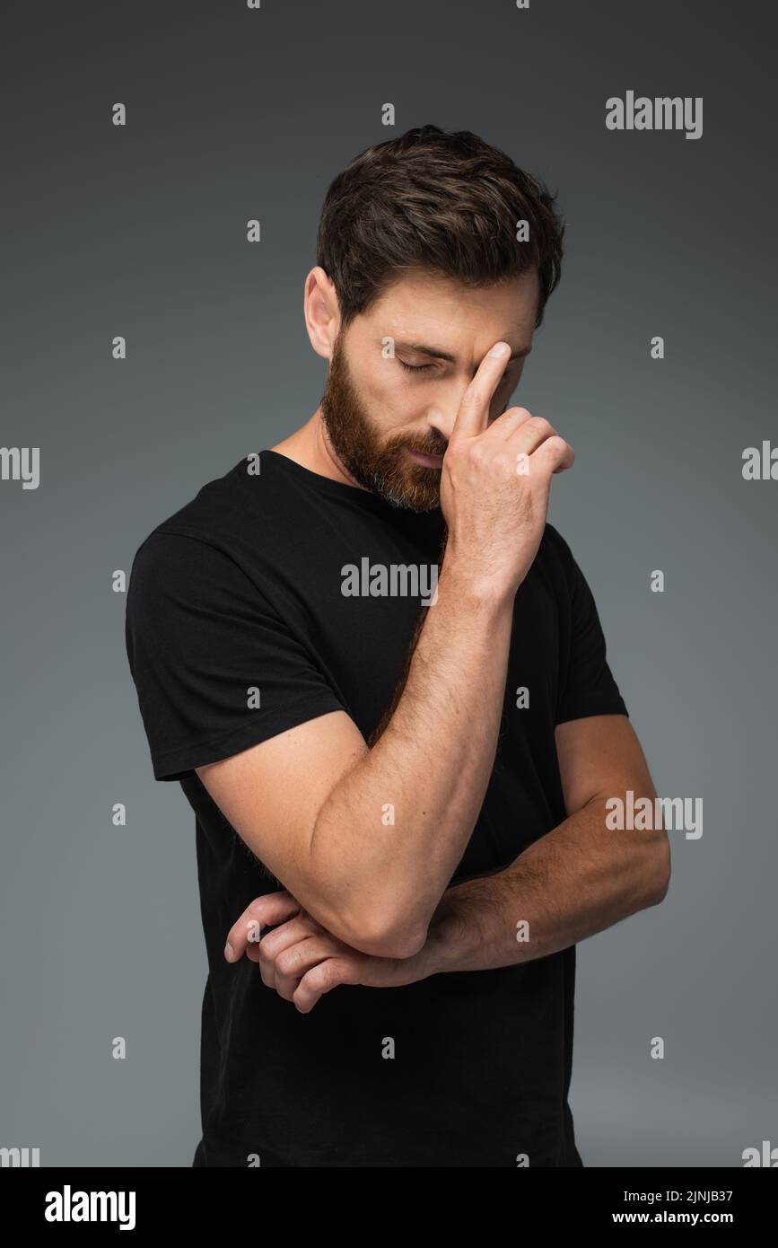retrato de hombre pensativo en camiseta negra con ojos cerrados aislados sobre imagen de archivo gris Foto de stock