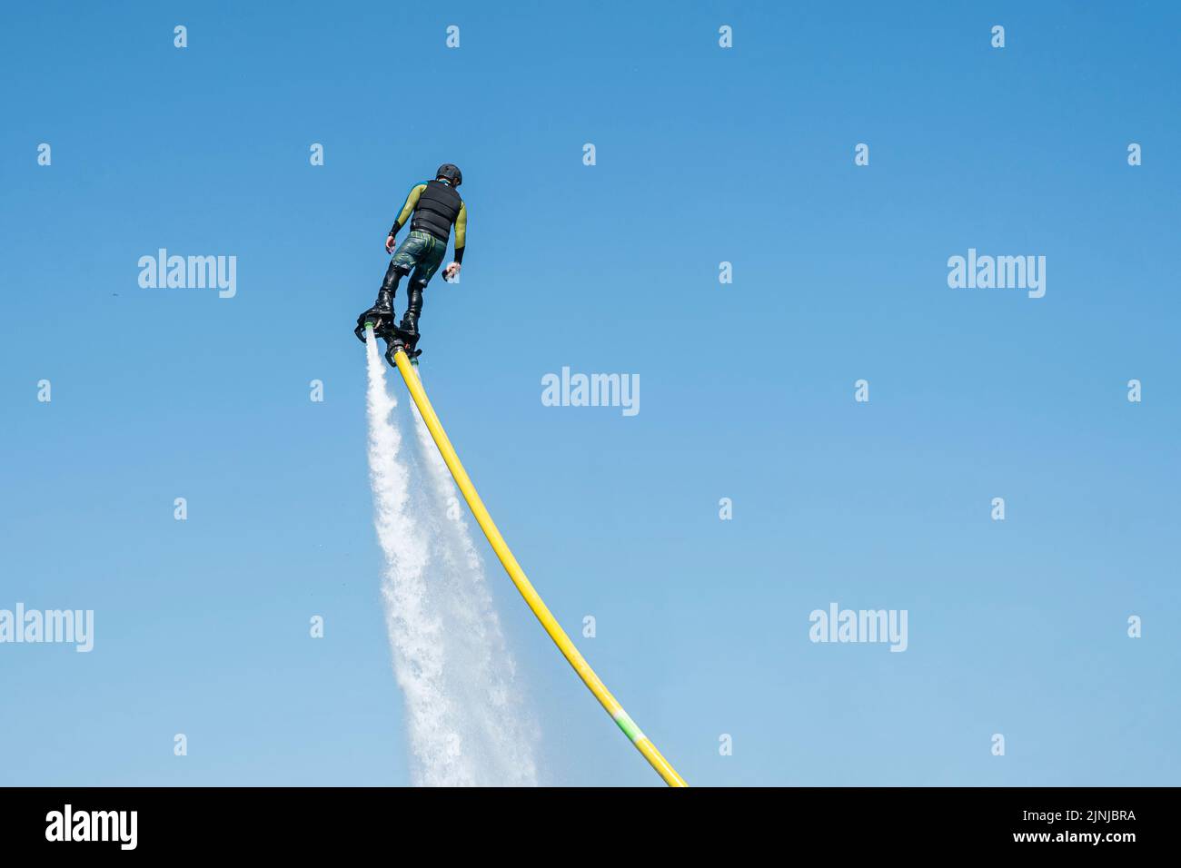 Un hombre vuela sobre un flyboard contra el fondo del cielo azul. Deporte EXTREMO Foto de stock