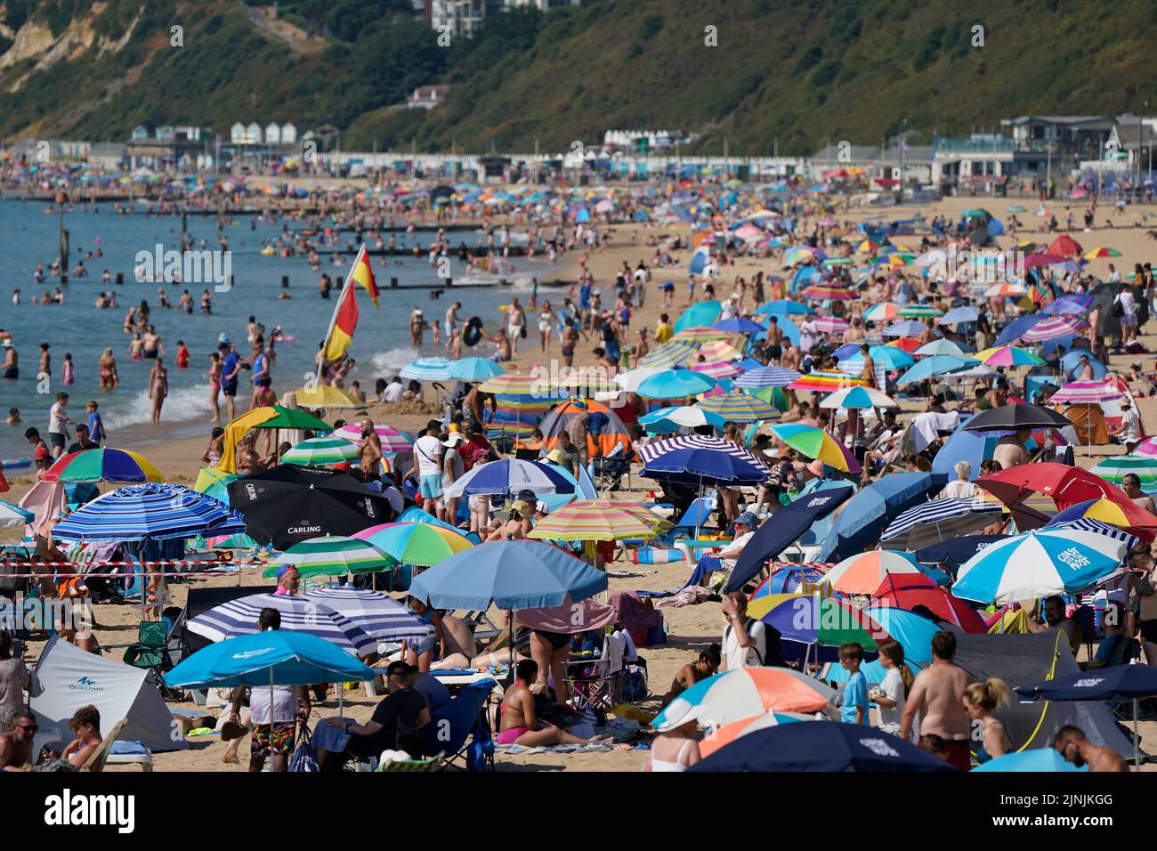 La gente se reúne en el clima caluroso de la playa de Bournemouth, Dorset. Está previsto que se declare una sequía en algunas partes de Inglaterra el viernes, con temperaturas que alcanzarán los 35C grados, lo que hace que el país sea más caliente que algunas partes del Caribe. Fecha de la foto: Viernes 12 de agosto de 2022. Foto de stock