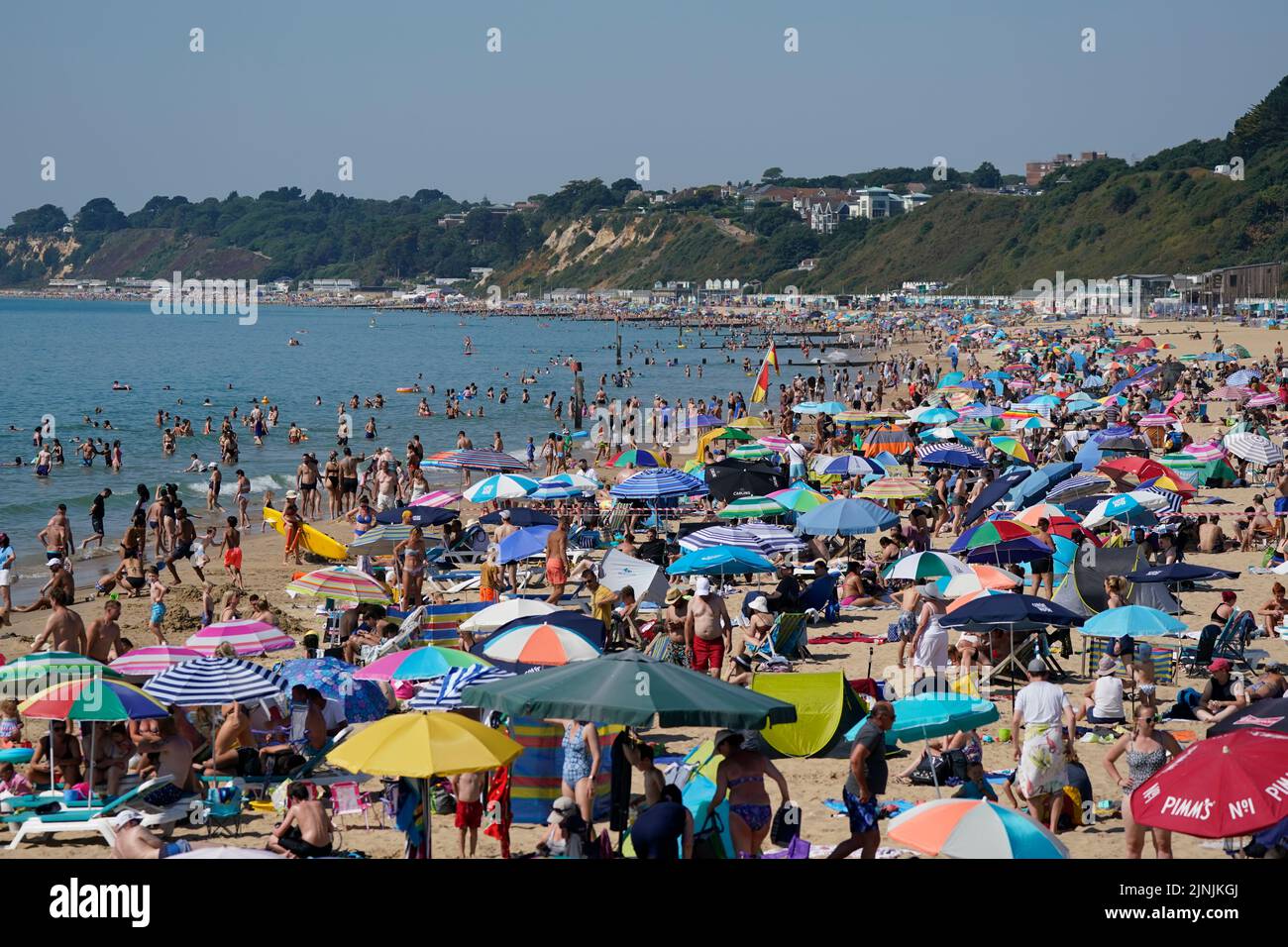 La gente se reúne en el clima caluroso de la playa de Bournemouth, Dorset. Está previsto que se declare una sequía en algunas partes de Inglaterra el viernes, con temperaturas que alcanzarán los 35C grados, lo que hace que el país sea más caliente que algunas partes del Caribe. Fecha de la foto: Viernes 12 de agosto de 2022. Foto de stock