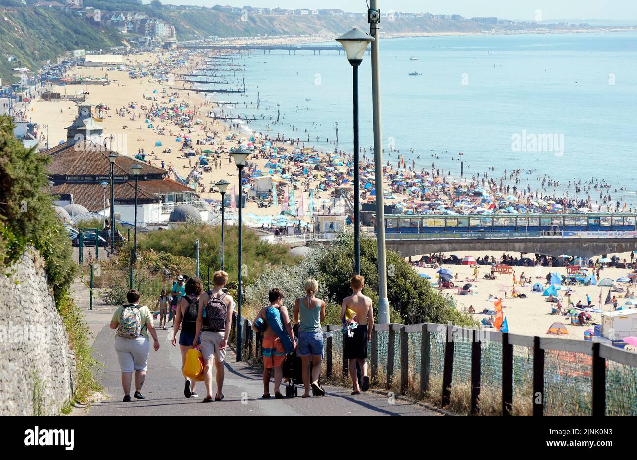 La gente hace su camino hacia la playa de Bournemouth en Dorset. Está previsto que se declare una sequía en algunas partes de Inglaterra el viernes, con temperaturas que alcanzarán los 35C grados, lo que hace que el país sea más caliente que algunas partes del Caribe. Fecha de la foto: Viernes 12 de agosto de 2022. Foto de stock