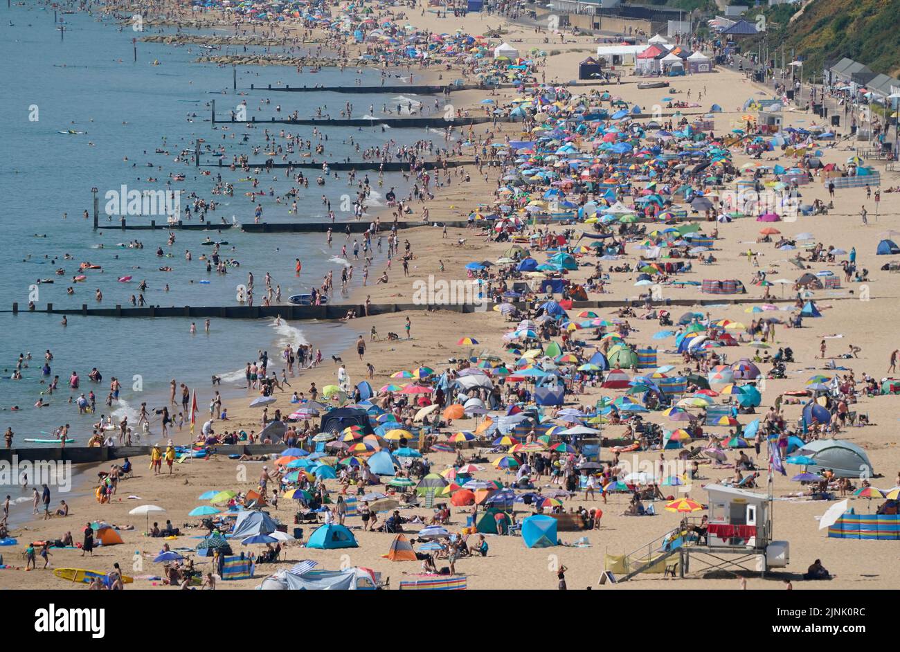 La gente se reúne en el clima caluroso en las playas de Durley y Alum Chine en Dorset. Está previsto que se declare una sequía en algunas partes de Inglaterra el viernes, con temperaturas que alcanzarán los 35C grados, lo que hace que el país sea más caliente que algunas partes del Caribe. Fecha de la foto: Viernes 12 de agosto de 2022. Foto de stock