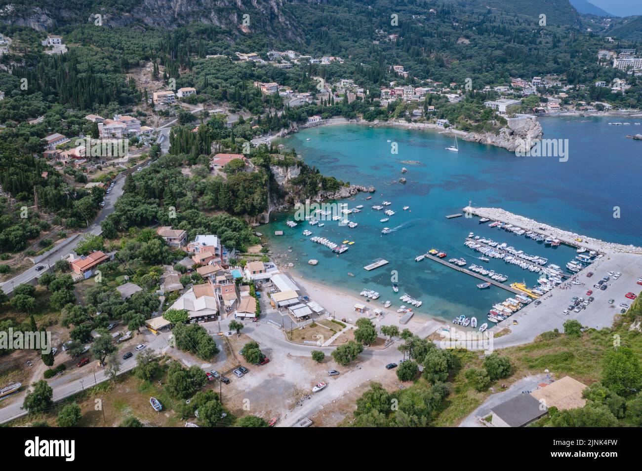 Bahía en forma de hogar en Palaiokastritsa famosa ciudad turística en la isla griega de Corfú, vista con la playa de Alypa y el puerto deportivo Foto de stock