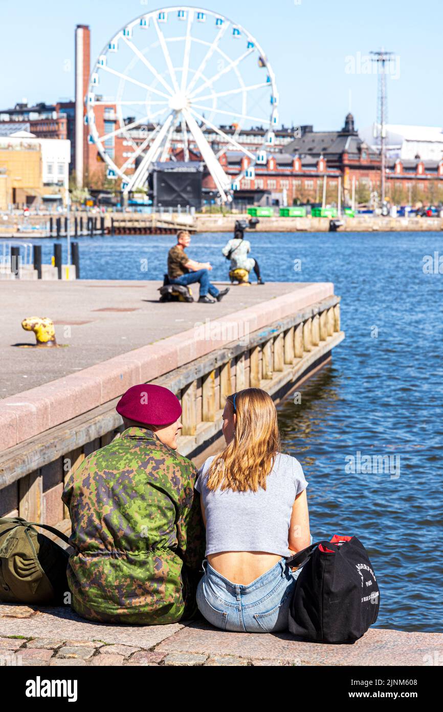 Una pareja joven sentada junto al puerto en Helsinki, Finlandia Foto de stock