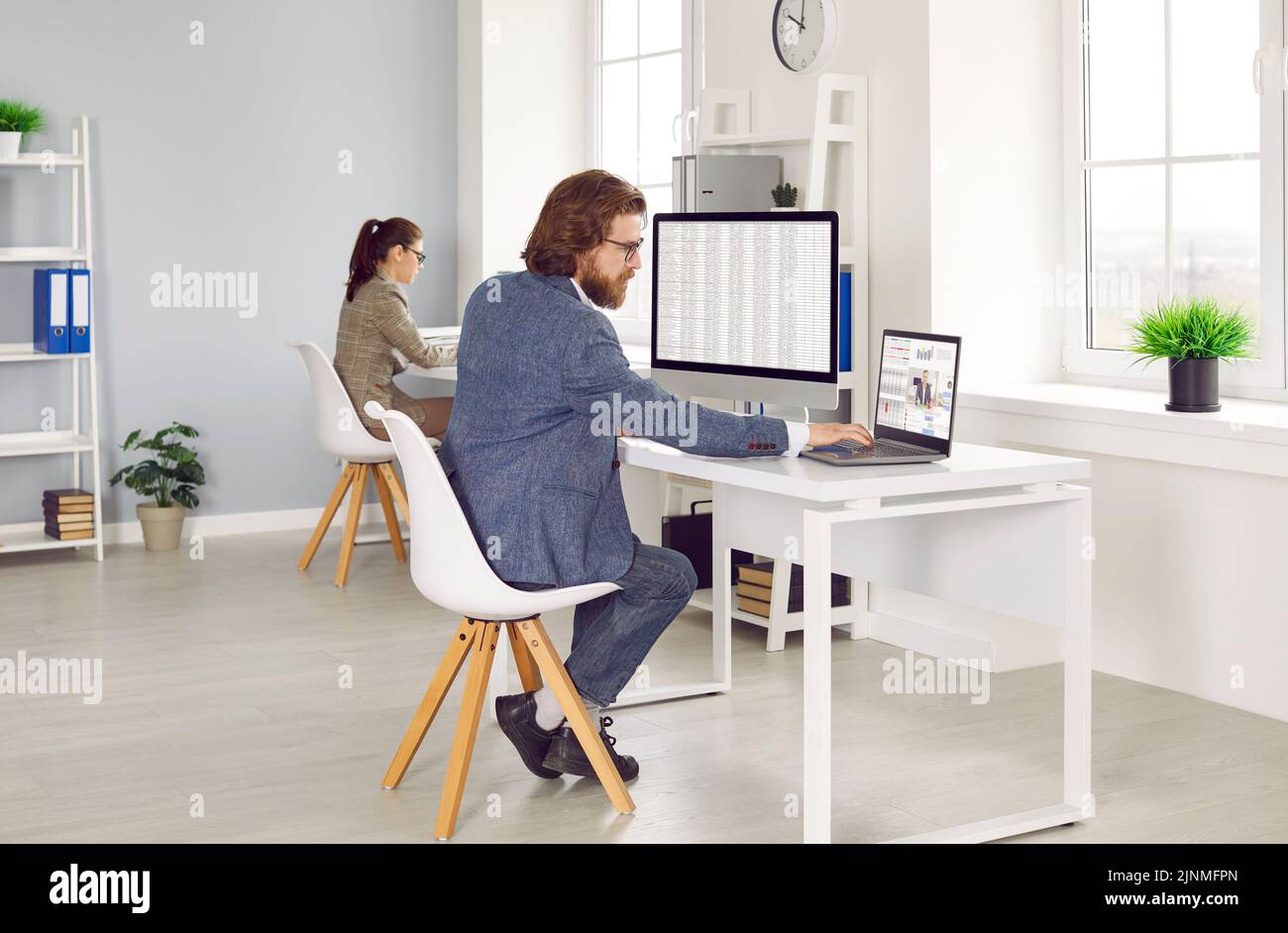 Dos contadores financieros profesionales que trabajan en computadoras en el interior moderno de la oficina Foto de stock