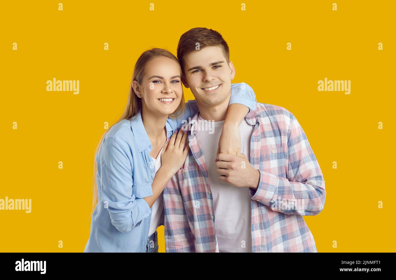 Feliz joven pareja caucásica hombre y mujer sonriendo posando con un ser querido se encuentra en el estudio amarillo Foto de stock