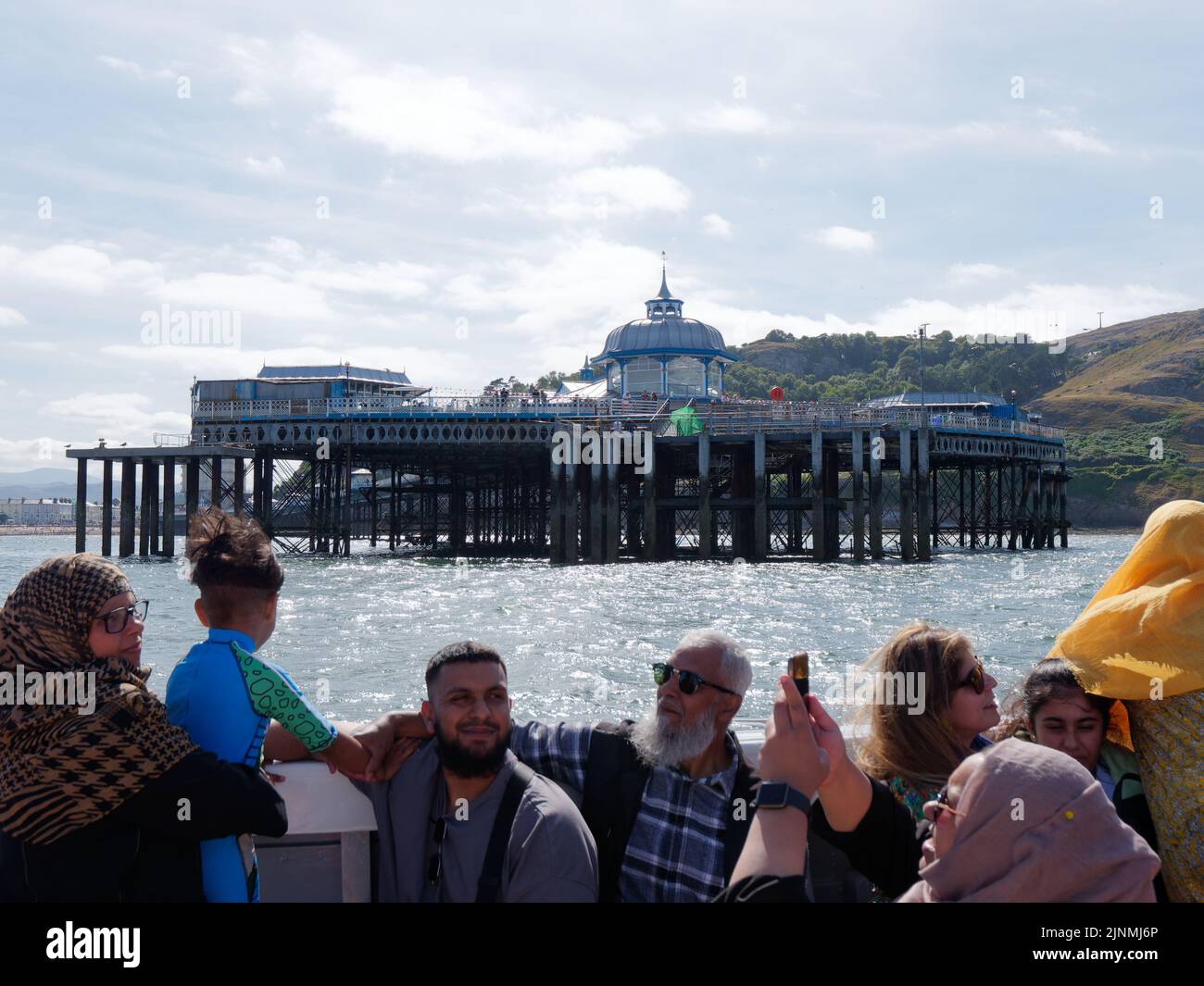 Llandudno, Clwyd, Gales, agosto de 07 2022: La gente disfruta de un viaje en barco con el muelle al fondo. Foto de stock