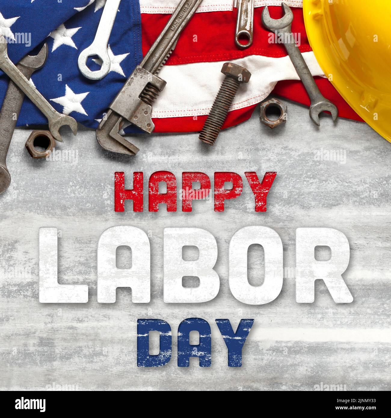 Bandera estadounidense con herramientas de trabajo sobre un fondo de madera blanca. Para la celebración del Día del Trabajo en EE.UU. Con texto Feliz Día del Trabajo. Foto de stock