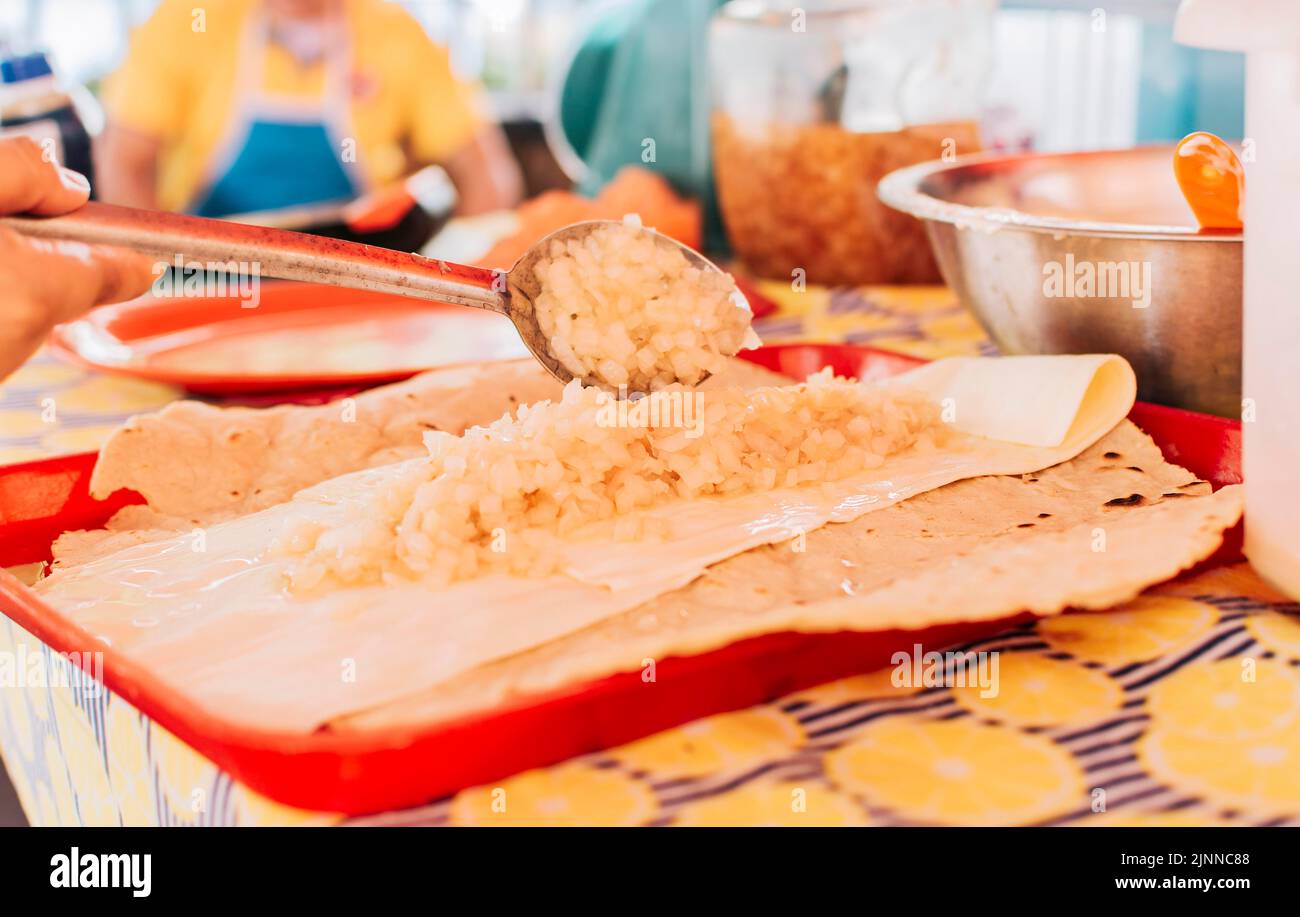 Vista del tradicional Quesillo con cebolla encurtida, Preparación del tradicional Quesillo Nicaragüense. Manos haciendo delicioso Quesillo Nicaragüense. Foto de stock