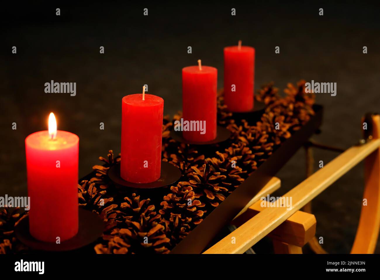 Cuatro velas de Adviento decoradas con conos de pino en un trineo, primera Adviento una vela encendida Foto de stock
