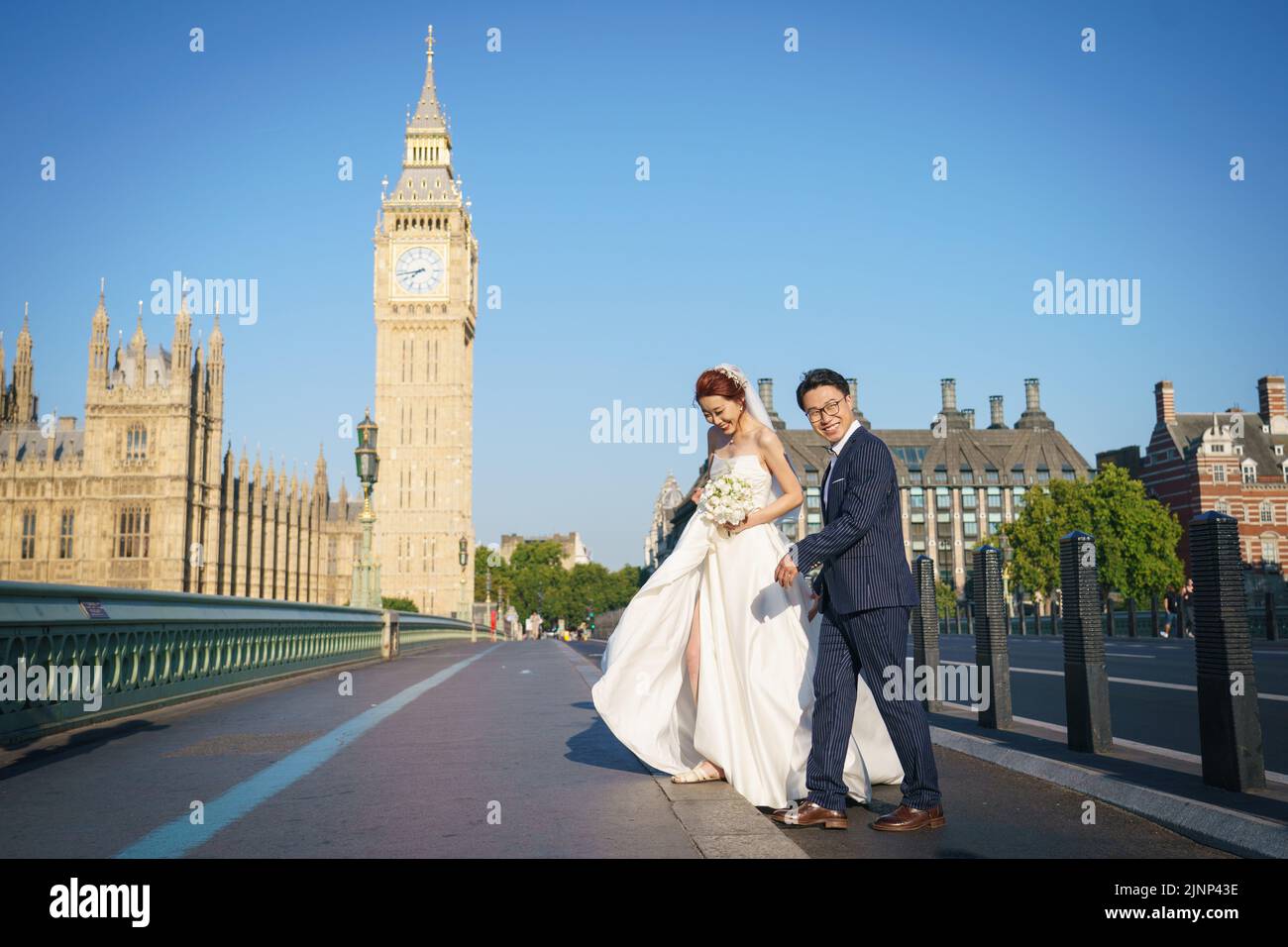 Posar un par para retratos de boda a primera hora de la mañana en el Puente de Westminster, Londres, ya que se ha declarado una sequía en algunas partes de Inglaterra tras el verano más seco de los últimos 50 años. Fecha de la foto: Sábado 13 de agosto de 2022. Foto de stock