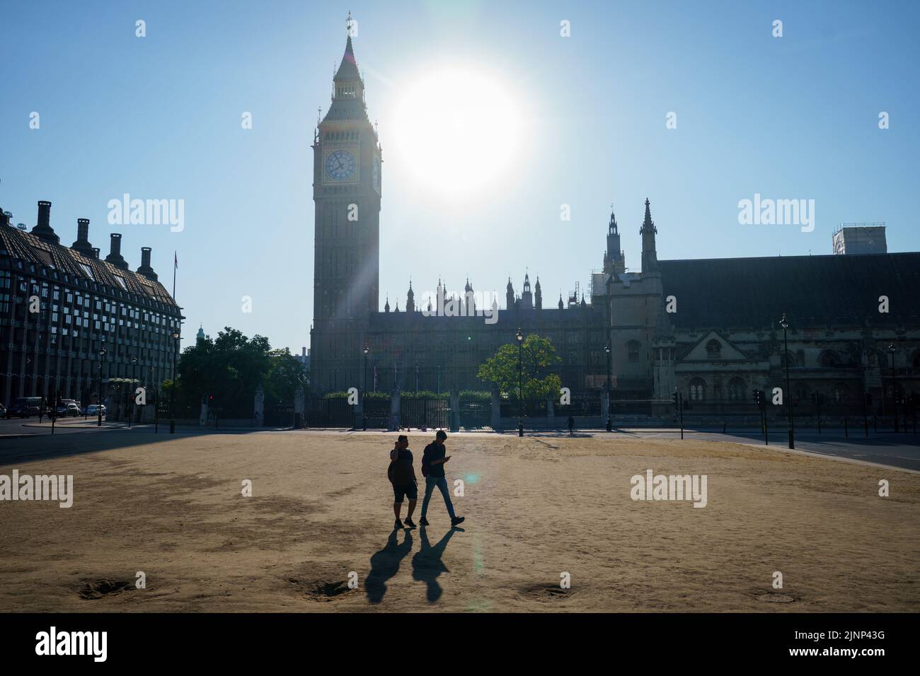Dos personas cruzan pasto reseco en Parliament Square, Westminster, Londres, como una sequía ha sido declarada en partes de Inglaterra después del verano más seco de 50 años. Fecha de la foto: Sábado 13 de agosto de 2022. Foto de stock