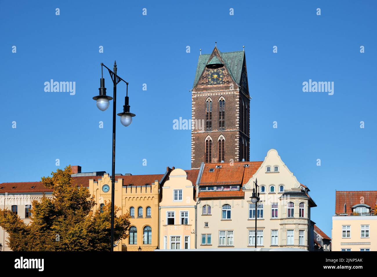 Antigua torre del reloj de la iglesia Marienkirche y edificios históricos en el centro de Wismar, Alemania Foto de stock