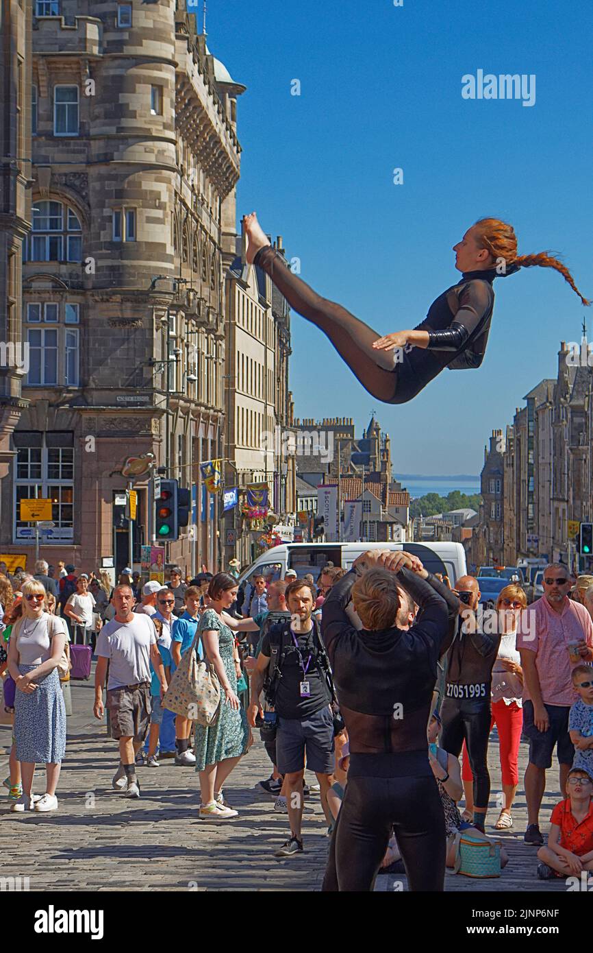 Edimburgo, Escocia, 11 de agosto de 2022, Festival Fringe en la Royal Mile Una joven dama con un traje negro que realiza un salto en medio del aire Foto de stock