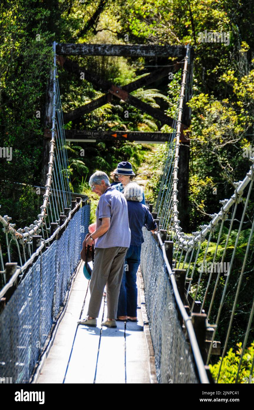 Visitantes en el puente colgante sobre el desfiladero de Hokitka, en la selva tropical de la costa oeste de la Isla del Sur en Nueva Zelanda Foto de stock