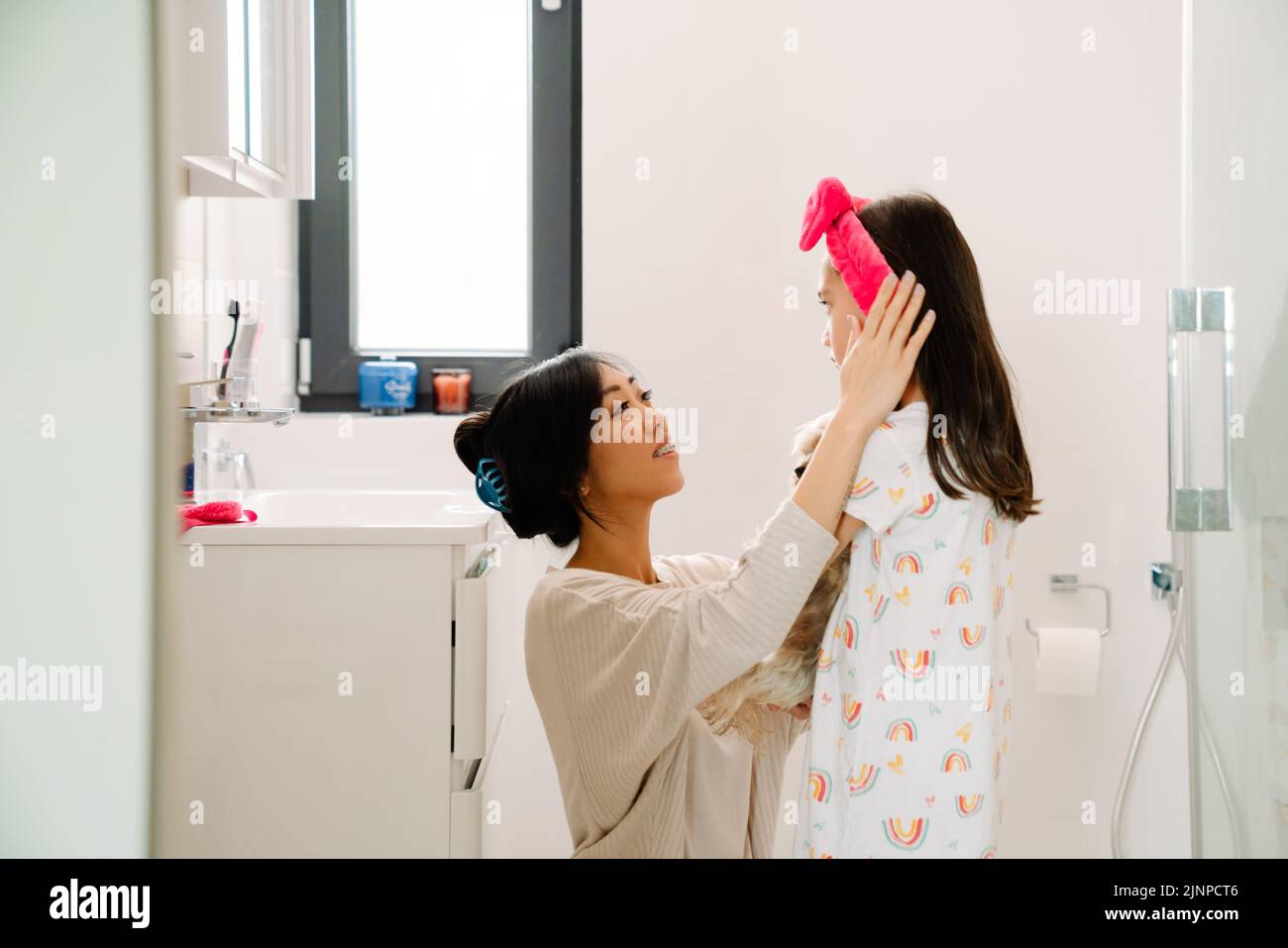 Madre asiática usando diadema en su hija en el baño en casa Foto de stock