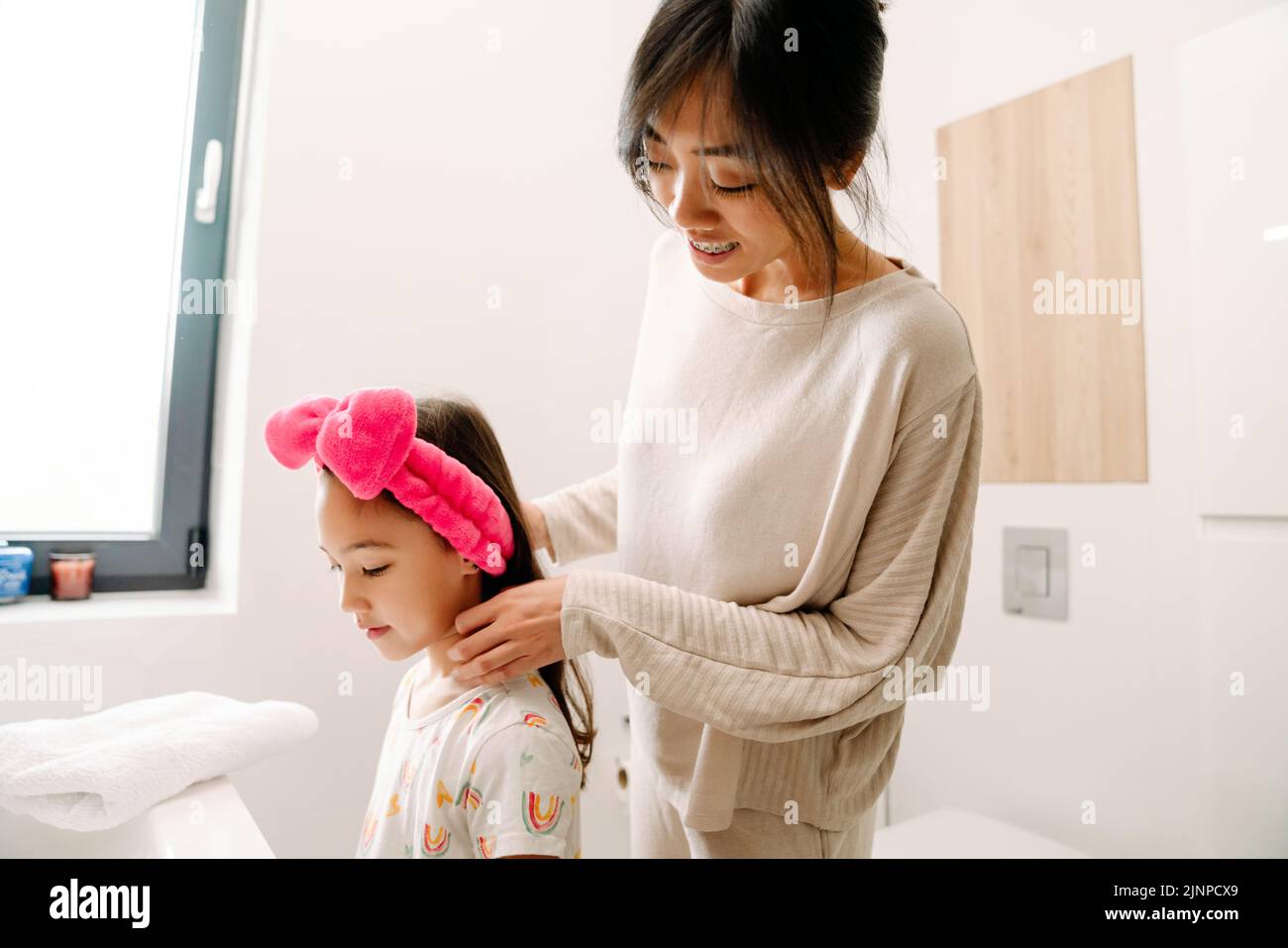 Madre asiática y su hija de pie juntas en el baño en casa Foto de stock