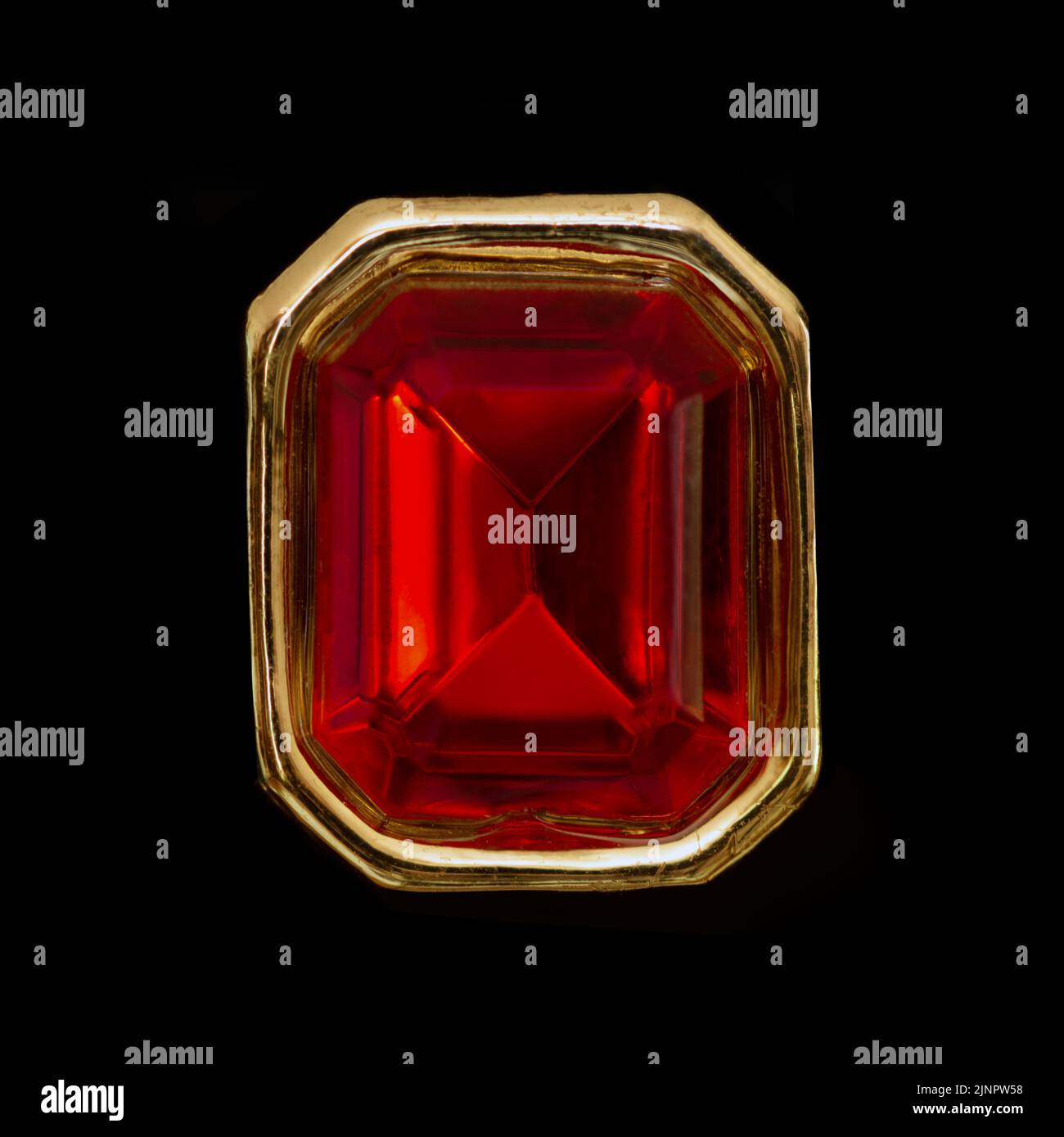 gema de rubí rojo poligonal sobre anillo dorado, fondo negro Foto de stock