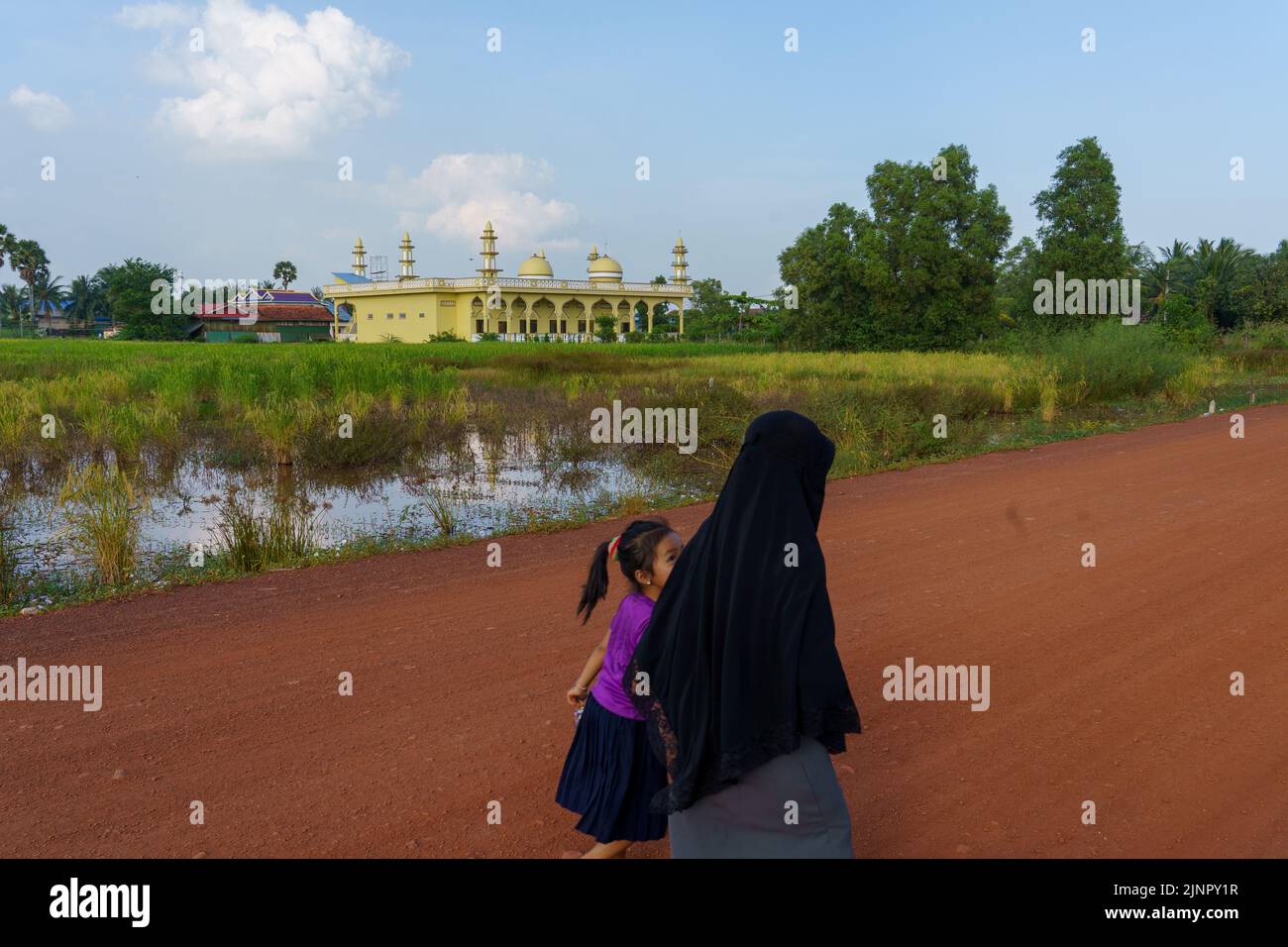 Mujer musulmana con hijab negro y ropa oscura caminando por el edificio  gris de la ciudad. la dama con expresión divertida representa el espacio de  copia de la cultura islámica.