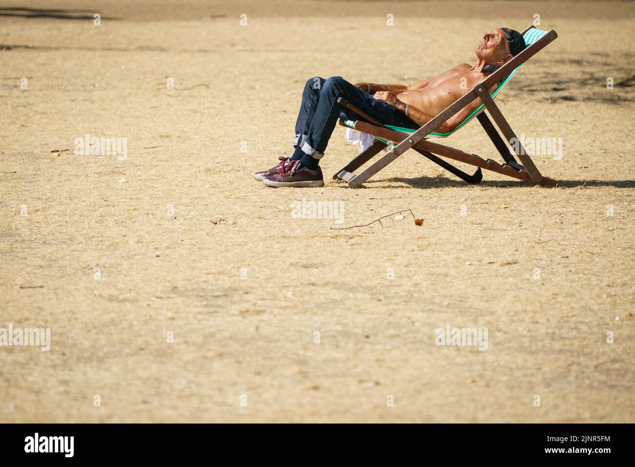 Un hombre se sienta al sol en Hyde Park, Londres, cuando se ha declarado una sequía en algunas partes de Inglaterra después del verano más seco de 50 años. Fecha de la foto: Sábado 13 de agosto de 2022. Foto de stock